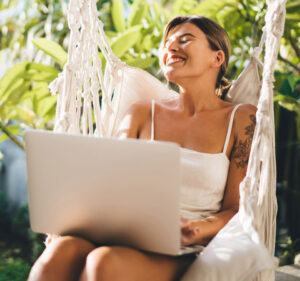 woman with laptop smiling in a swing
